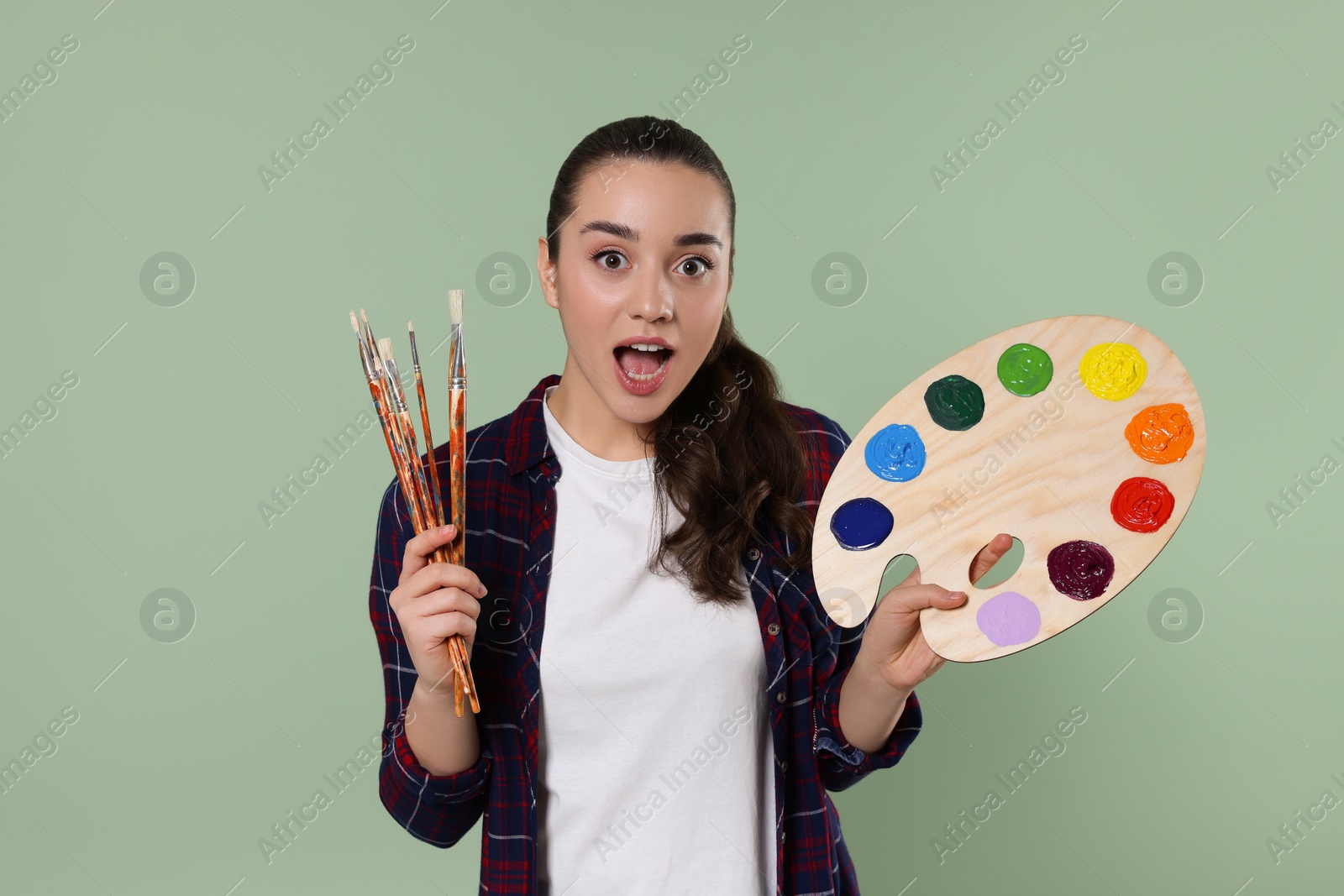 Photo of Woman with painting tools on pale green background. Young artist