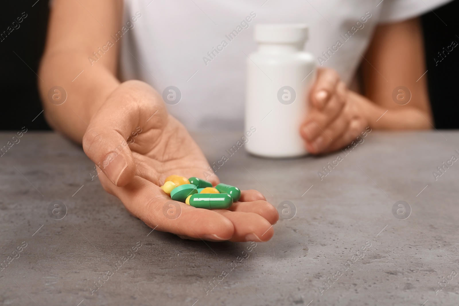 Photo of Woman holding different pills at table, closeup