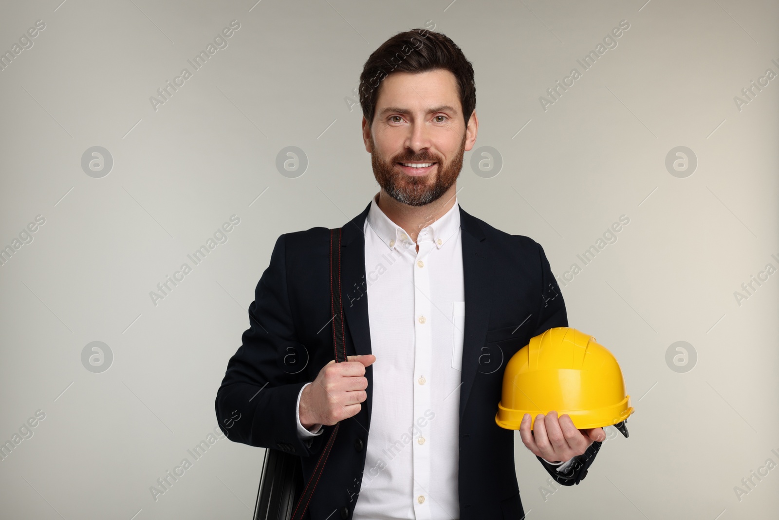 Photo of Architect with drawing tube and hard hat on gray background