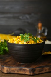 Photo of Bowl with tasty boiled corn on wooden table