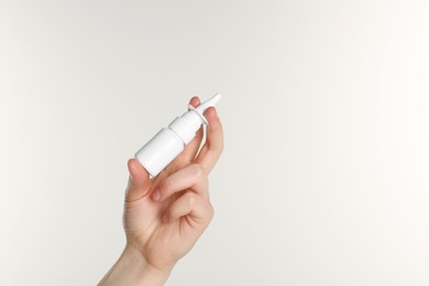 Photo of Woman holding nasal spray on white background, closeup. Space for text
