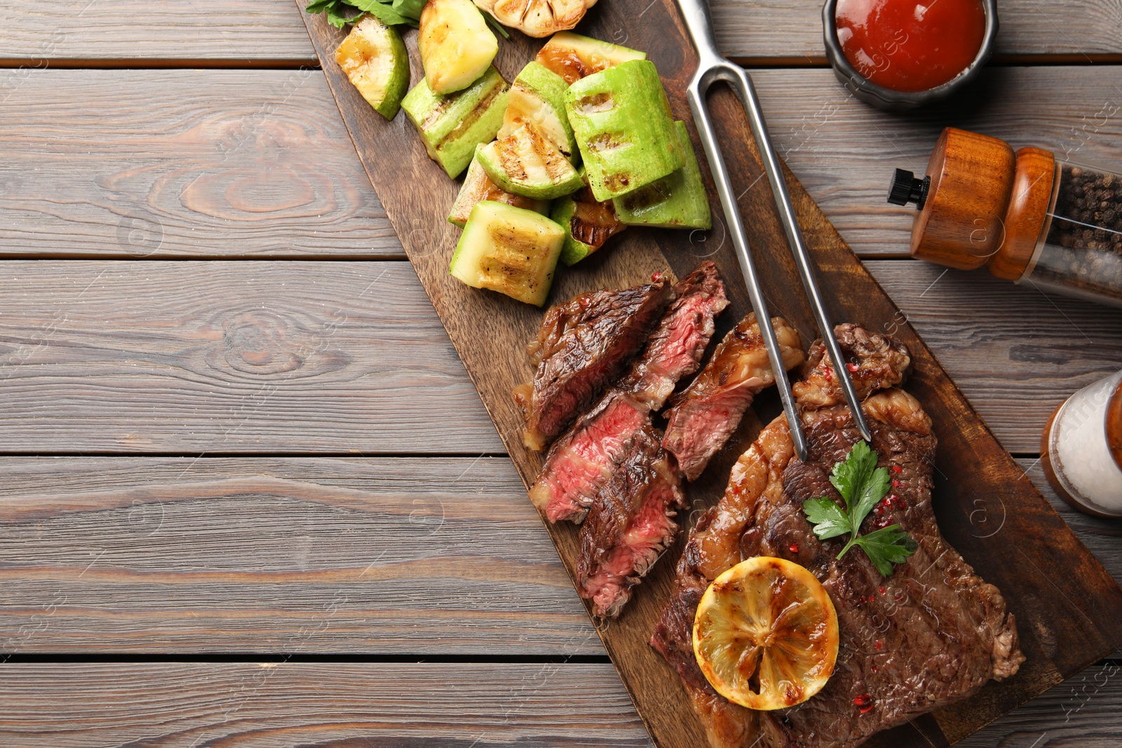 Photo of Delicious grilled beef steak and vegetables served on wooden table, flat lay. Space for text