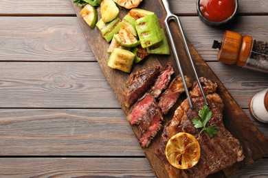Delicious grilled beef steak and vegetables served on wooden table, flat lay. Space for text