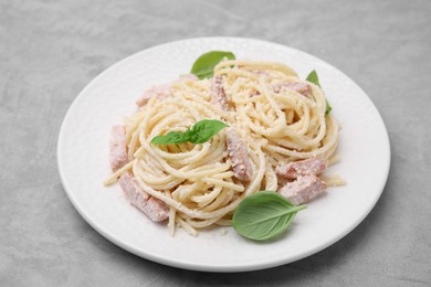 Photo of Plate of tasty pasta Carbonara with basil leaves on grey table