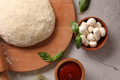 Photo of Pizza dough, products and rolling pin on gray textured table, flat lay