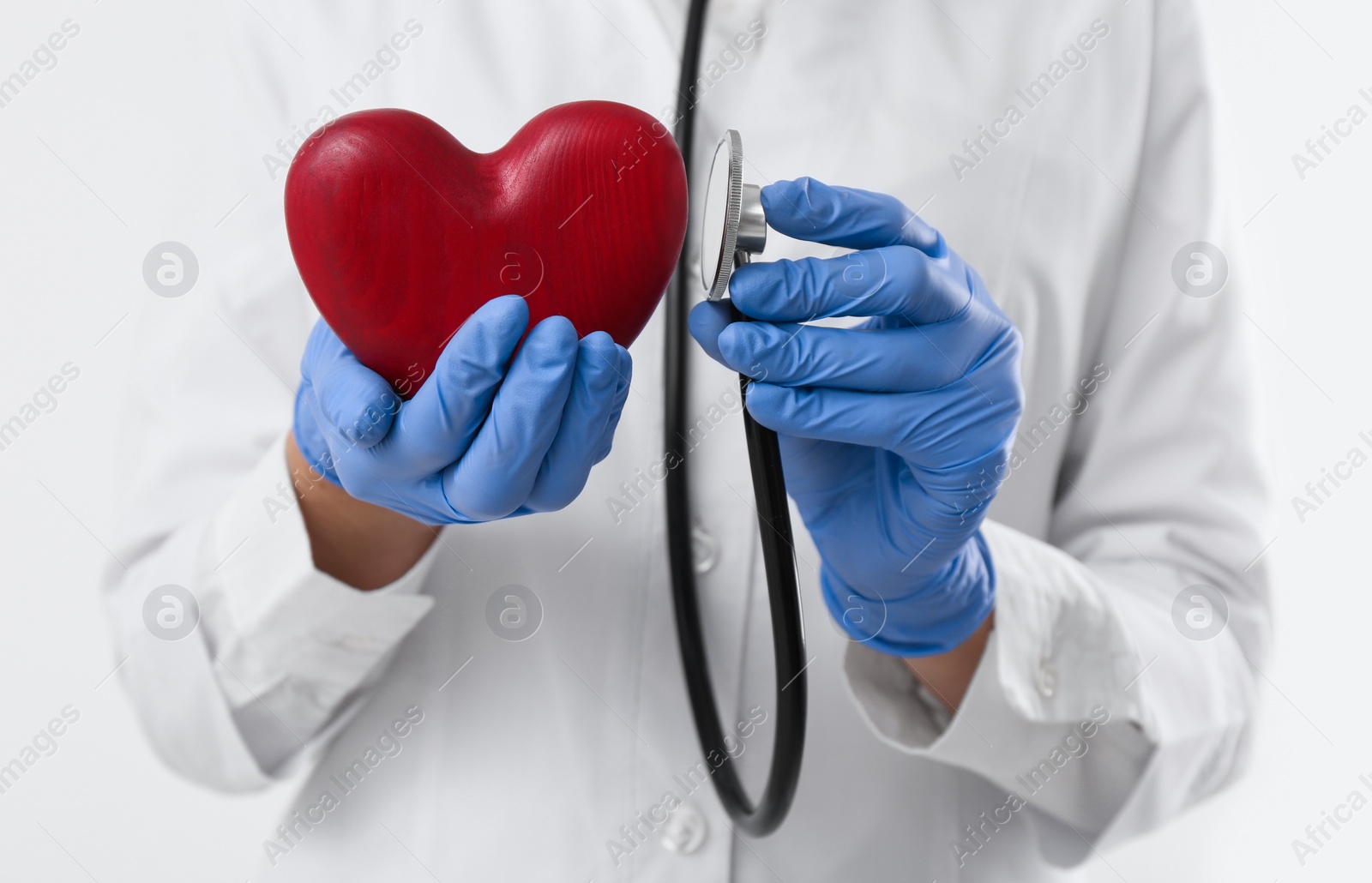 Photo of Doctor with stethoscope and red heart on white background, closeup. Cardiology concept