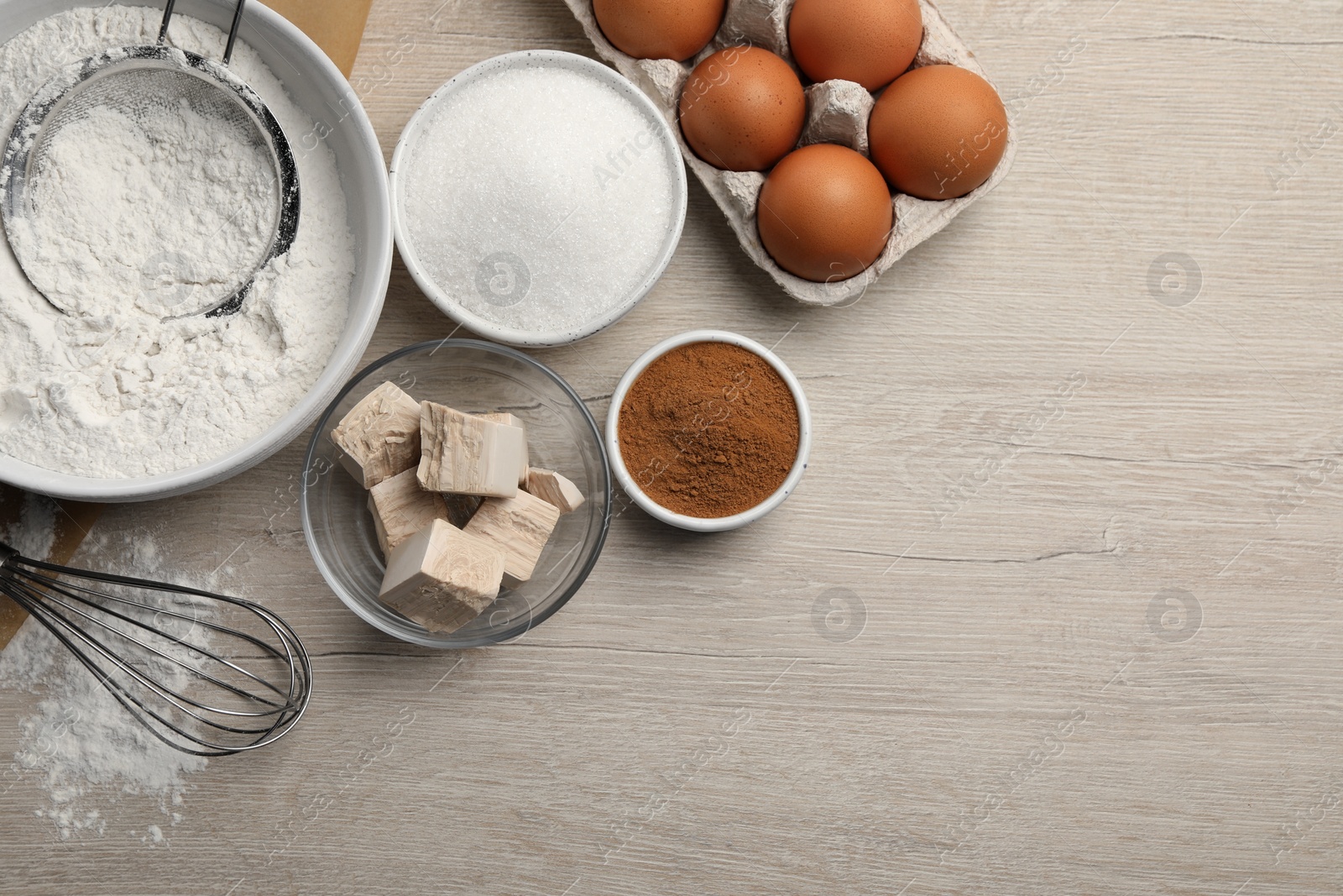 Photo of Flat lay composition with flour, leaven and different ingredients on white wooden table, space for text. Cooking yeast cake