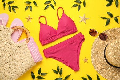 Stylish bikini and beach accessories on yellow background, flat lay