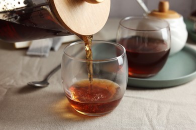 Photo of Pouring warm tea into cup on light table, closeup