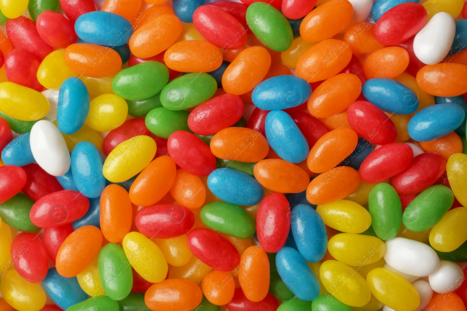 Photo of Tasty bright jelly beans as background, top view