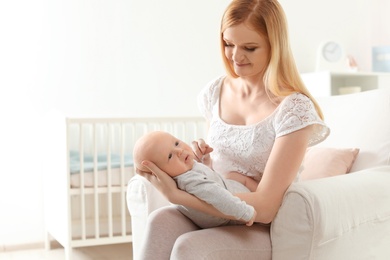 Photo of Happy mother with her baby sitting in armchair at home