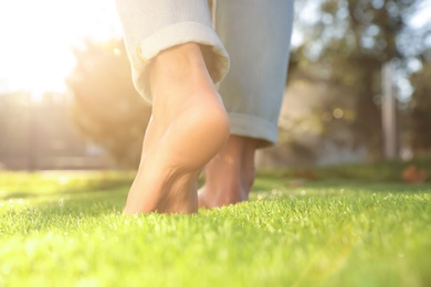 Photo of Man walking barefoot on fresh green grass, closeup