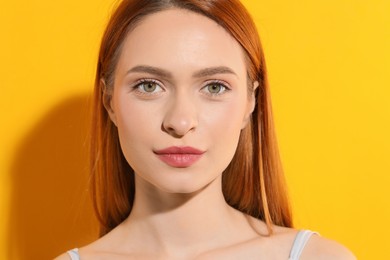 Beautiful young woman with makeup on orange background