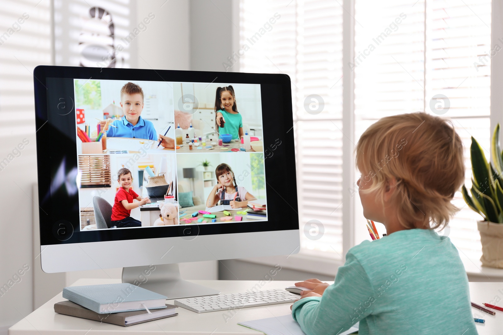 Photo of Little boy studying with classmates via video conference at home. Distance learning during COVID-19 pandemic