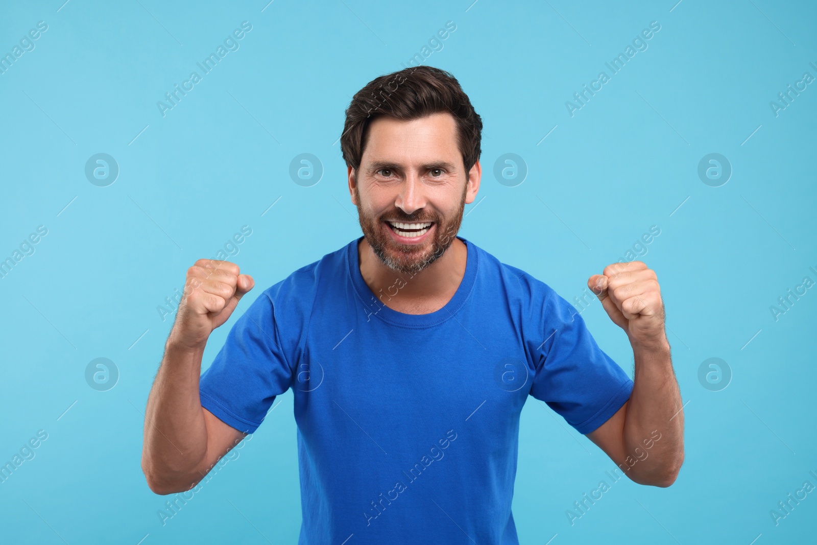 Photo of Emotional sports fan celebrating on light blue background