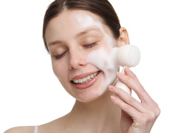 Young woman washing face with brush and cleansing foam on white background