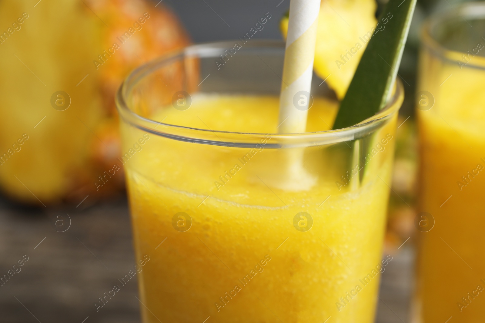 Photo of Glass of tasty pineapple smoothie on table, closeup