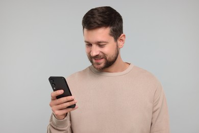 Photo of Happy man using smartphone on light grey background