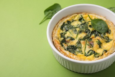 Photo of Delicious pie with spinach on green background, closeup. Space for text