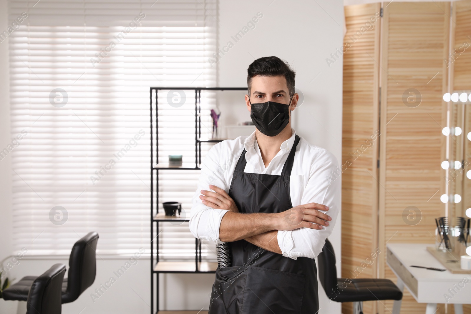 Photo of Professional stylist with protective mask in salon. Hairdressing services during Coronavirus quarantine