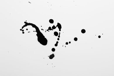 Photo of Blots of black ink on white background, top view