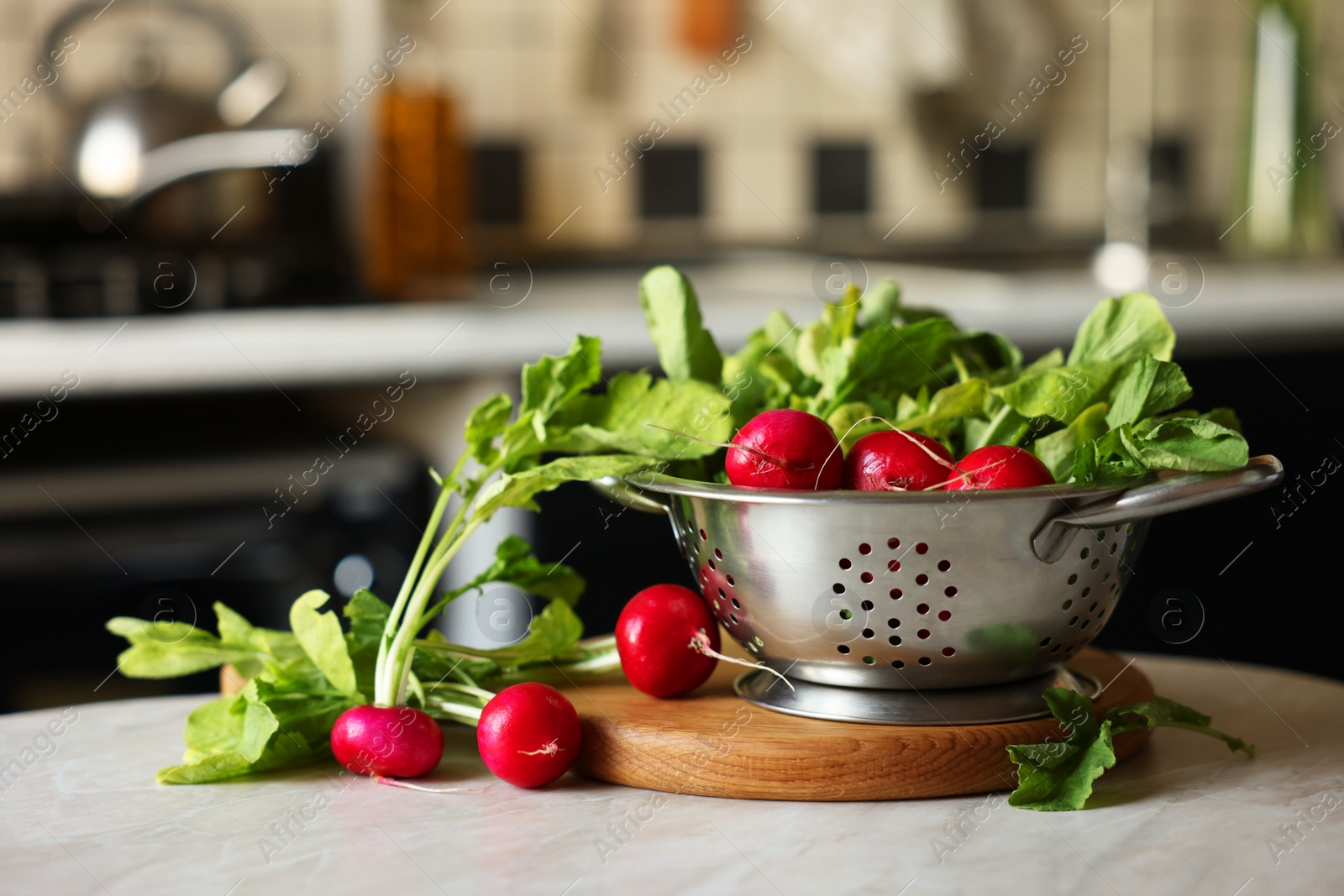 Photo of Metal colander with fresh radishes on white table