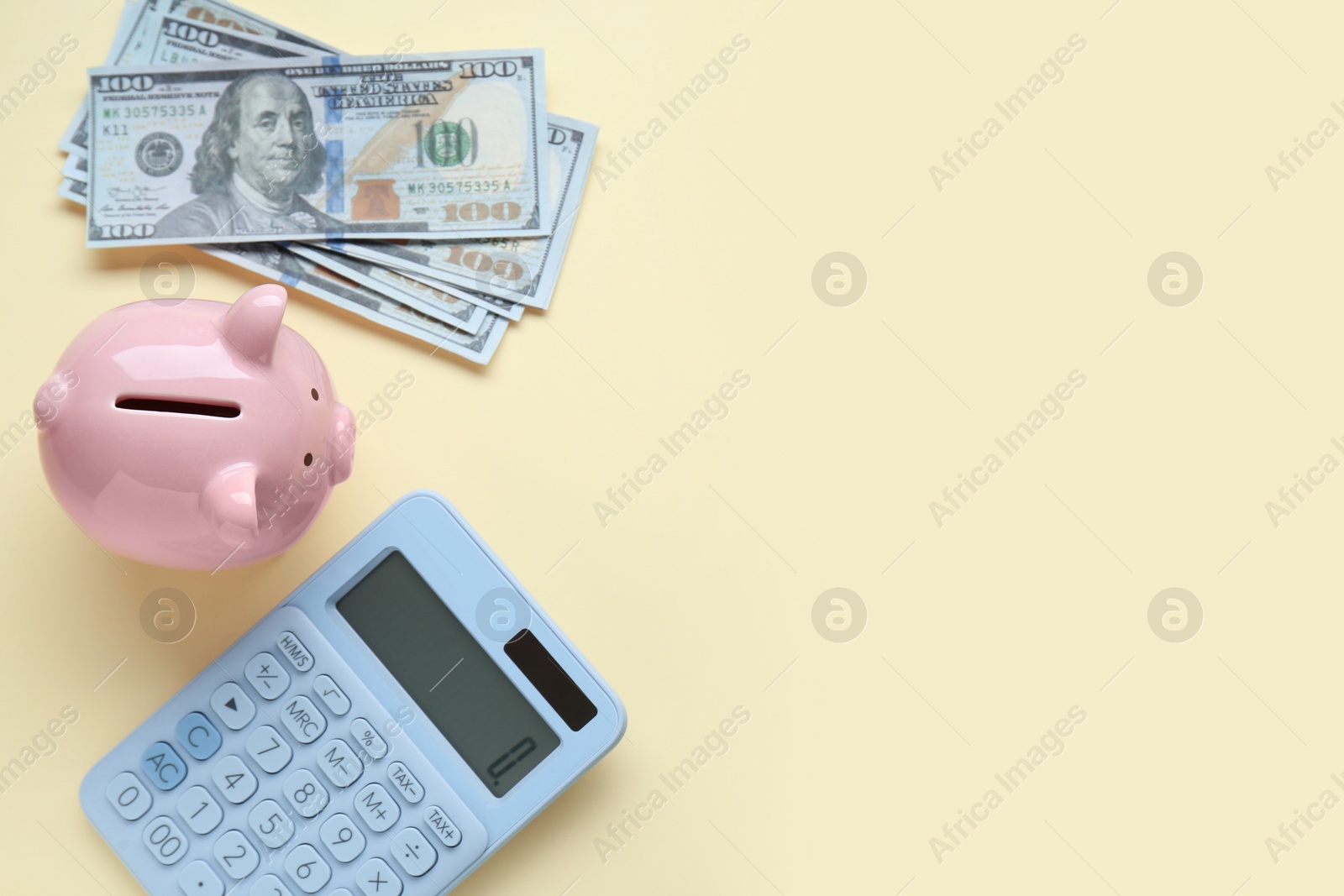 Photo of Piggy bank, banknotes and calculator on beige background, flat lay. Space for text
