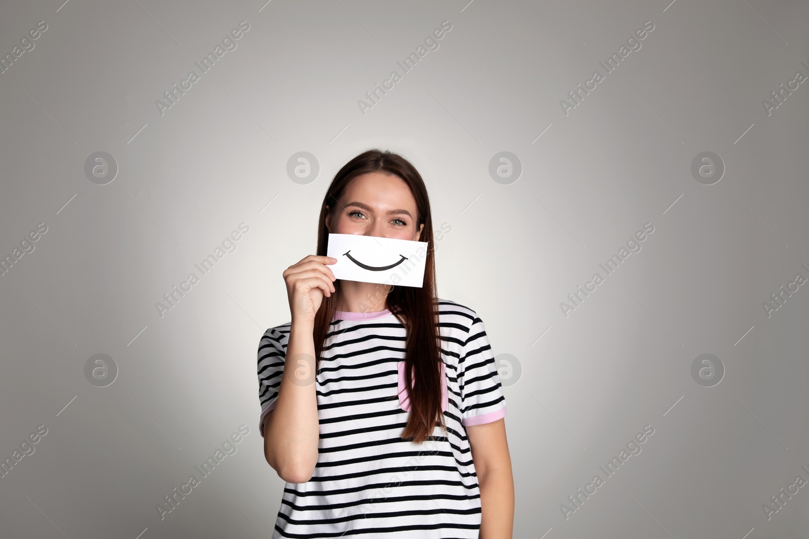Photo of Woman holding sheet of paper with smile on grey background