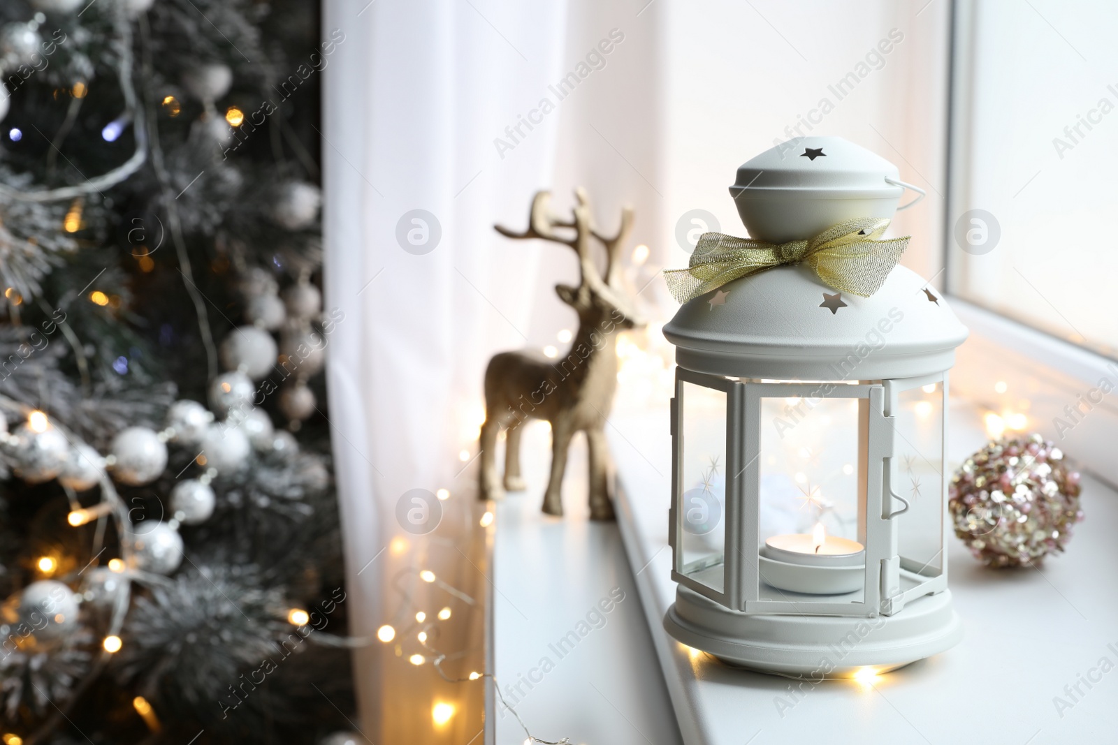 Photo of Beautiful Christmas lantern and other decorations on window sill in room