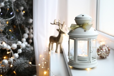 Photo of Beautiful Christmas lantern and other decorations on window sill in room