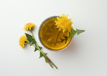 Photo of Delicious fresh tea and dandelion flowers on white background, top view