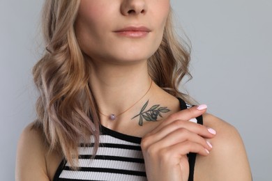 Photo of Beautiful woman with tattoo on body against grey background, closeup