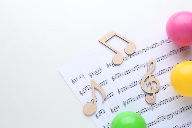 Wooden notes, music sheets and toy balls on white background, top view with space for text. Baby song concept