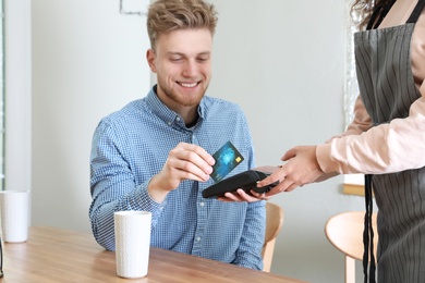 Client using credit card machine for non cash payment in cafe