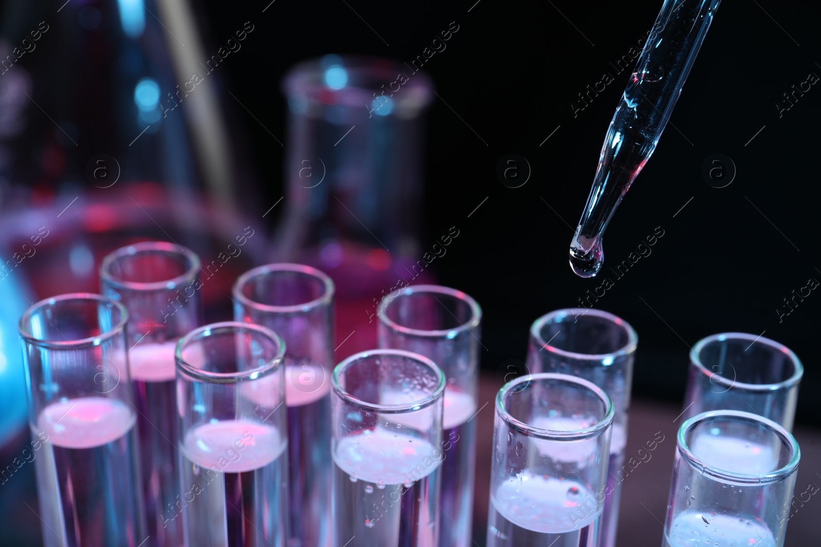 Photo of Dripping reagent into test tube on black background, closeup. Laboratory analysis