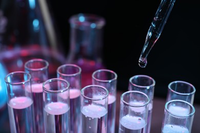 Photo of Dripping reagent into test tube on black background, closeup. Laboratory analysis