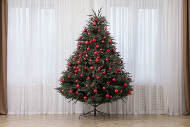 Beautifully decorated Christmas tree near window indoors