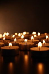 Photo of Burning candles on surface in darkness, closeup