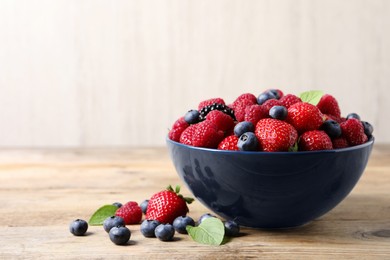 Different fresh ripe berries on wooden table. Space for text