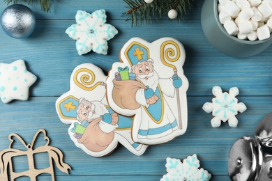 Photo of Delicious gingerbread cookies on blue wooden table, flat lay. St. Nicholas Day celebration