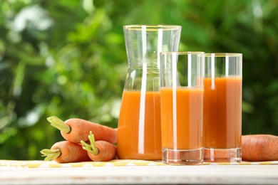 Composition with carrot drink on table against blurred background, space for text