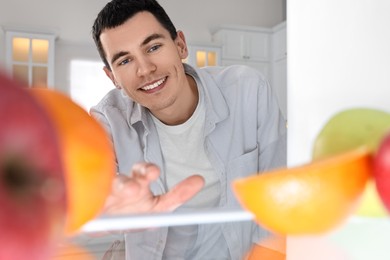 Happy man near refrigerator in kitchen, view from inside