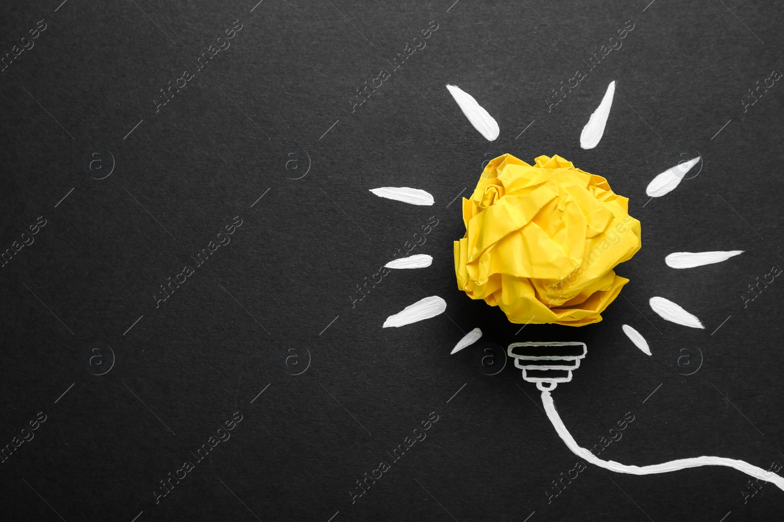 Photo of Composition with crumpled paper ball and drawing of lamp bulb on blackboard, top view. Idea concept