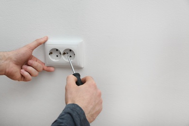 Photo of Electrician repairing wall sockets on white background, closeup. Space for text