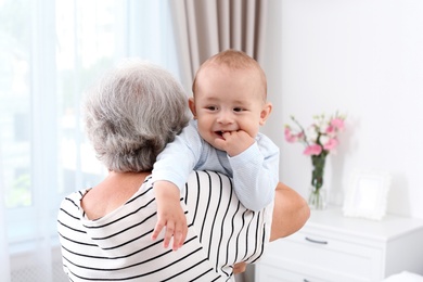 Photo of Cute little baby with grandmother at home
