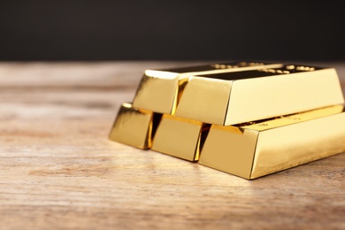 Photo of Precious shiny gold bars on wooden table