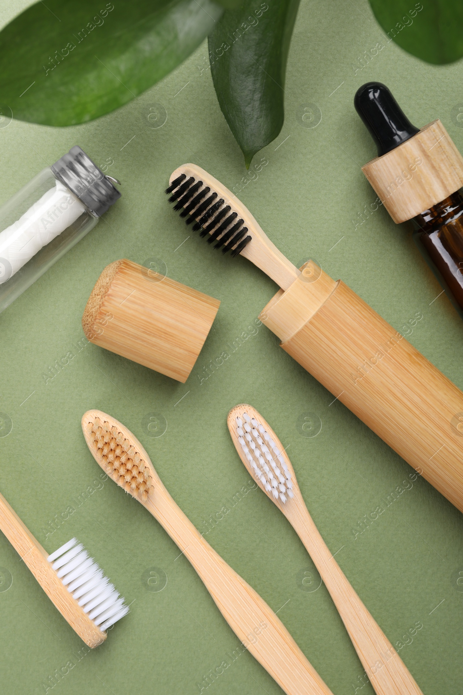 Photo of Flat lay composition with bamboo toothbrushes on green background