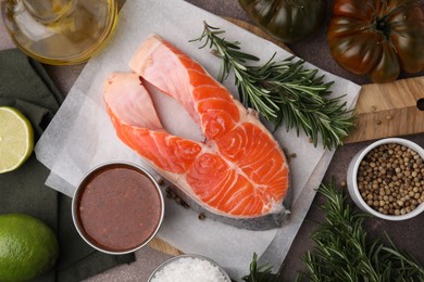 Photo of Fresh fish, products and marinade on brown table, flat lay