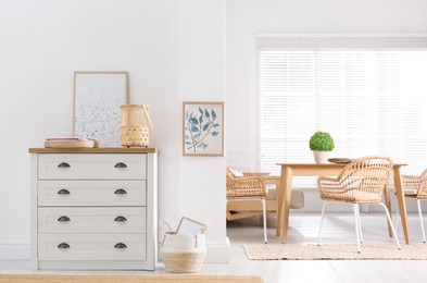 Photo of Stylish wicker holder with candle on chest of drawers indoors