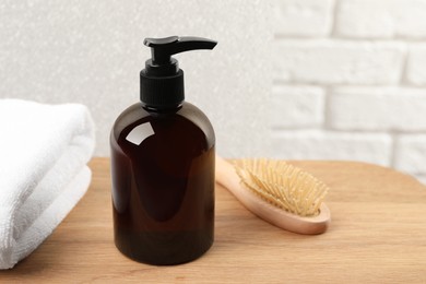 Photo of Shampoo bottle, towel and brush on wooden table